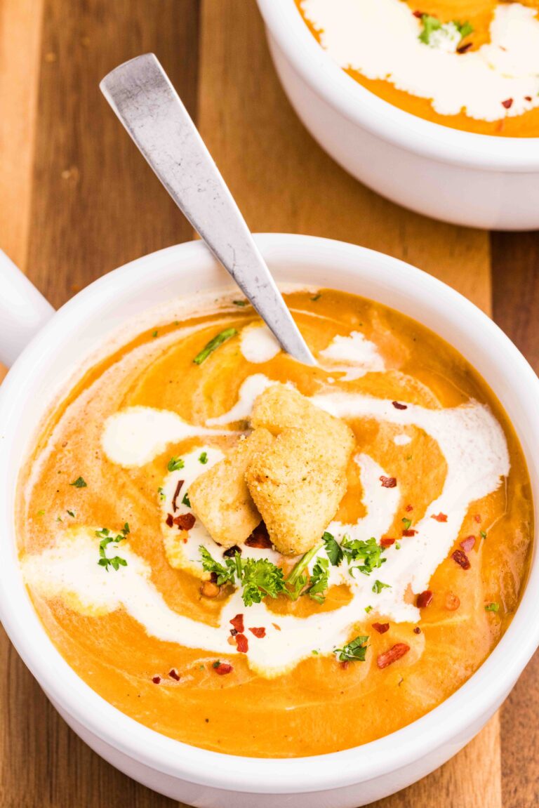 A bowl of creamy carrot and lentil soup with a drizzle of cream on top.